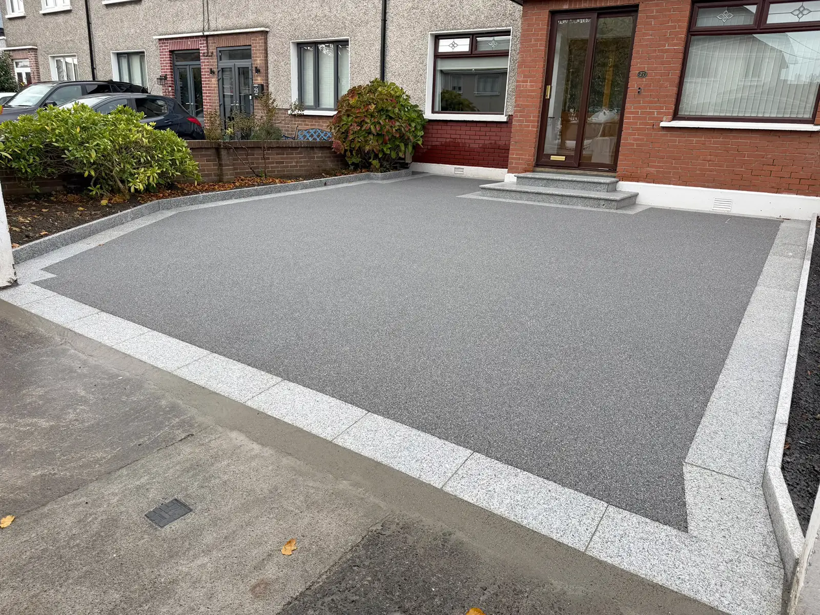 Side view of the grey resin driveway showing silver granite bullnose steps, borders and planting-area risers