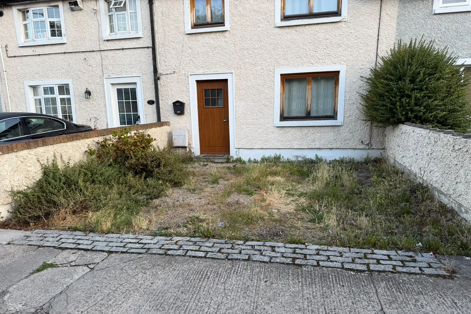 Existing uneven driveway with extensive weed growth and natural stone cobblelock in Drimnagh Dublin before replacement